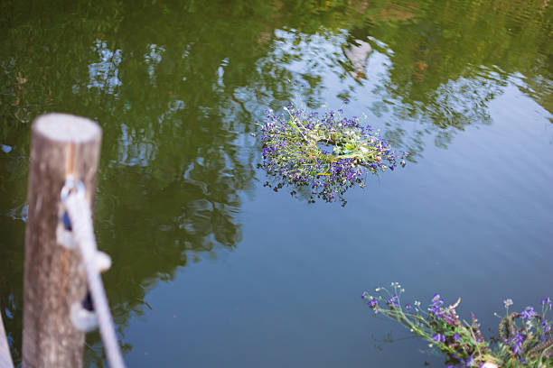 Kupala night flower wreath floating on the water surface near a wooden pier