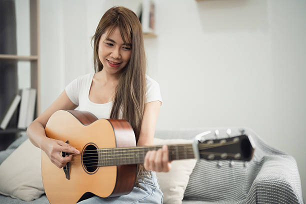 istock Young woman performs music in cozy home setting, playing acoustic guitar, enjoying creative expression and showcasing her passion for music in living room 2230609210