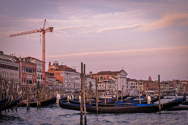 Venice, Italy - June 24, 2025: Red construction vessel moves through Venice canal, surrounded by historic buildings and reflecting on the tranquil water
