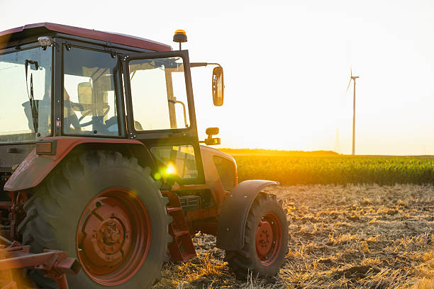 istock Agricultural tractor is working on the field with wind turbines. 2230620623