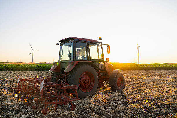istock Agricultural tractor is working on the field with wind turbines. 2230622166
