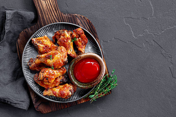 istock Fried chicken wings with ketchup on grey plate and dark background top view copy space for text 2230623942