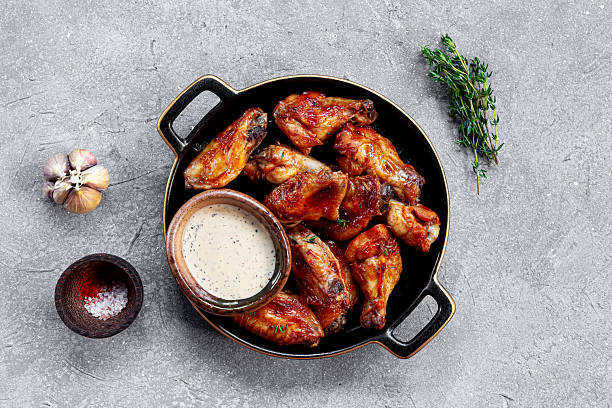 istock Fried chicken wings with sauce on black plate and grey background top view 2230623984