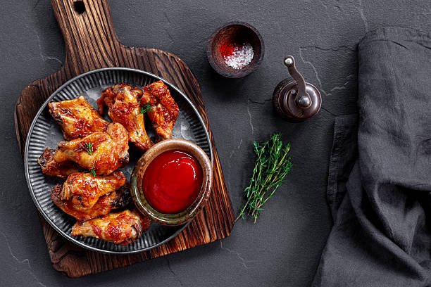istock Fried chicken wings with ketchup on grey plate and dark background top view 2230624271