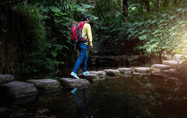 istock Female backpacker walking on stepping stones 2230625487