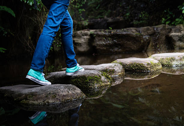 Woman legs walking on stepping stones