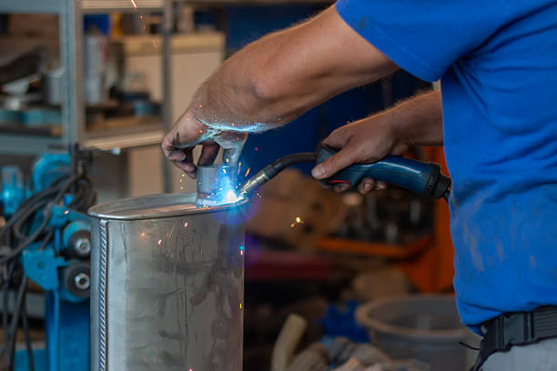 Master replacing of  muffler of exhaust system in car workshop. The mechanic is welding the car exhaust pipe.