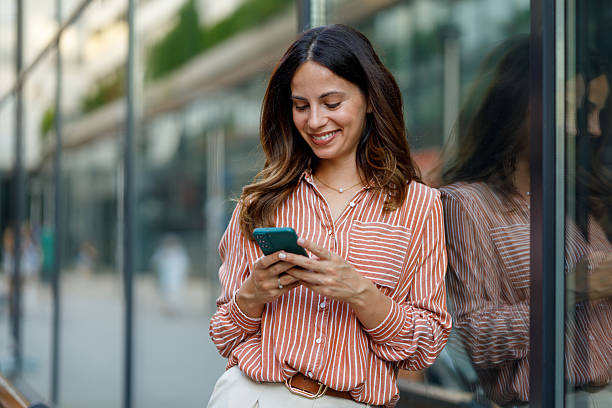 istock Young businesswoman smiling while using her smartphone in a bustling urban setting, embracing modern connectivity and city life 2230628635