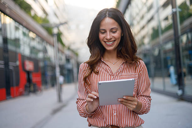 istock Professional woman navigating urban landscape, working on digital tablet with confident stride and wireless connectivity 2230629391