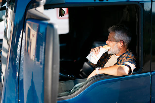 istock Truck driver eating sandwich during lunch break inside cabin 2230629789