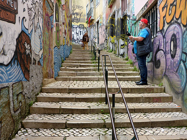 Lisbon, Portugal - March 6 2017 Tourist looking at the street art in Lisbon on the Escadinhas de São Cristóvão (stairs of Saint Christopher)