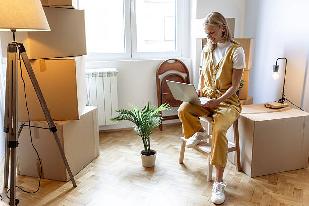 istock Woman working on laptop while unpacking in her new home 2230632601