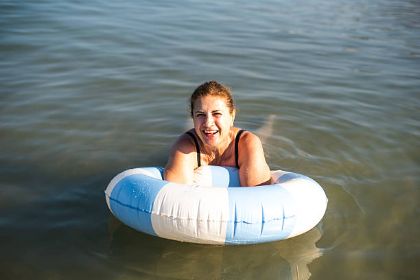 Woman is lounging on a floating ring in clear water, enjoying the sun