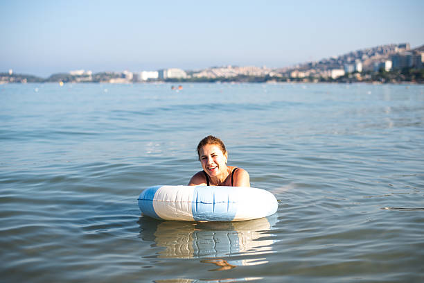 Woman is lounging on a floating ring in clear water, enjoying the sun