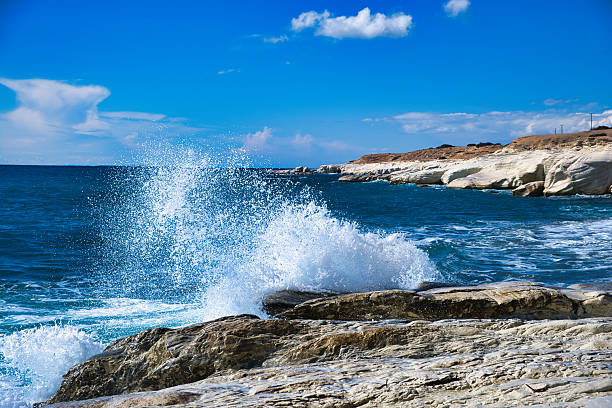Close-up view of waves crashing against rocky coastline in Arikok National Park, Aruba, with vibrant blue water.
