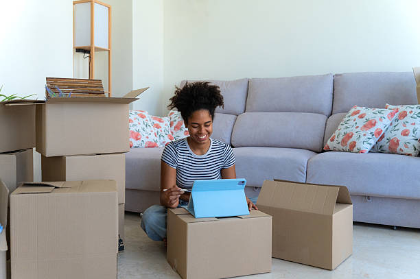 istock Young woman organizing her new home using a tablet surrounded by cardboard boxes 2230665992