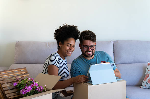 istock Couple decorating new home using tablet and cardboard boxes 2230666550