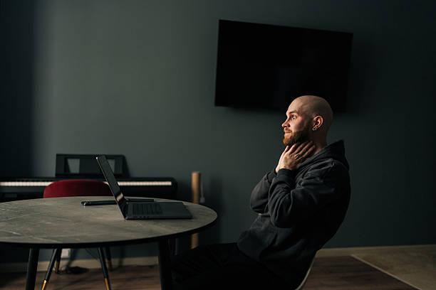 istock Tired freelancer touching neck while sitting at home office desk with laptop, looking pensive and contemplative after long day of work. 2230671991