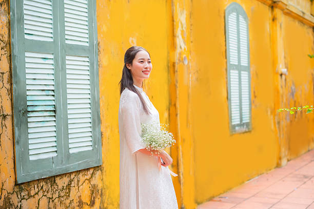 A Vietnamese woman in a traditional white dress at a landmark in Hanoi, the capital of Vietnam.