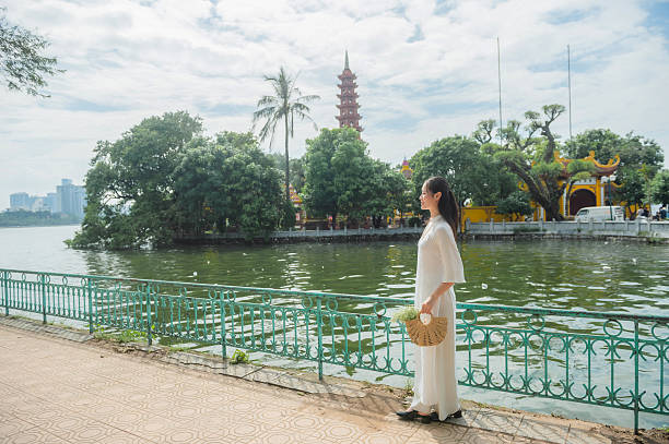 A Vietnamese woman in a traditional white dress at a landmark in Hanoi, the capital of Vietnam.