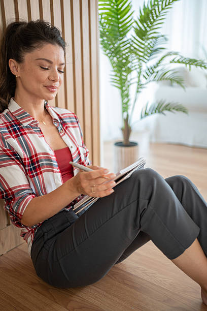 istock Young woman relaxing and writing in notebook at home 2230690099