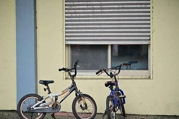 Taiwan - Mar 15, 2025: Against the pale exterior of a building, a larger and smaller bicycle stand side by side. The soft light and muted colors evoke a peaceful, everyday moment.