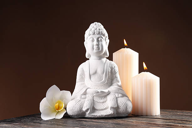istock Buddha statue, flower and candles on brown background 2230692678