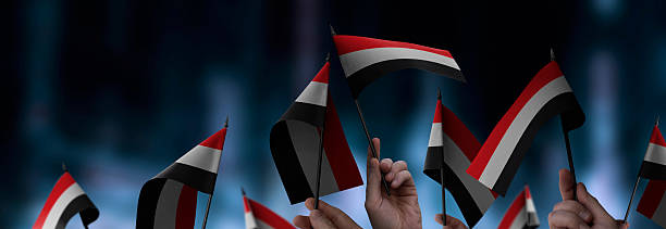 istock Yemen flags in their hands on a blurred urban background 2230694592