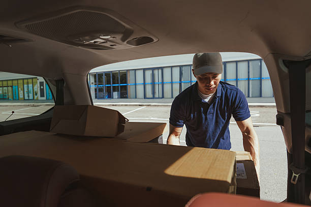 istock Asian Chinese delivery man unloading boxes from the back of vehicle 2230695484
