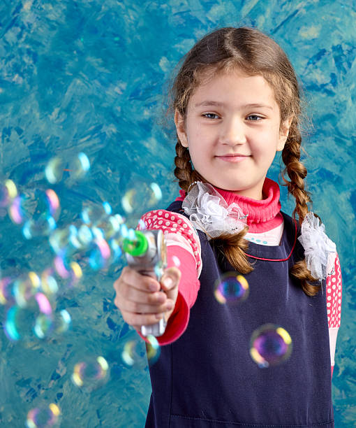 A little girl is playing with a bubble machine in the plum grove