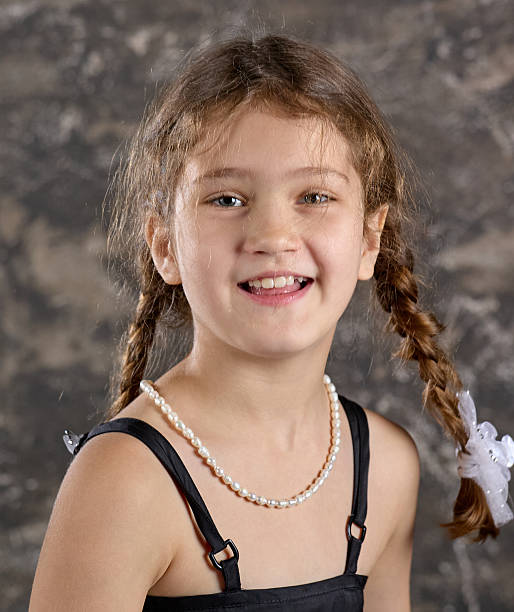 Portrait of cute elementary age girl with two funny pigtails is smiling looking at the camera. Studio shooting