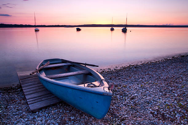 amazing soft pink sunset on lake with old wooden boat