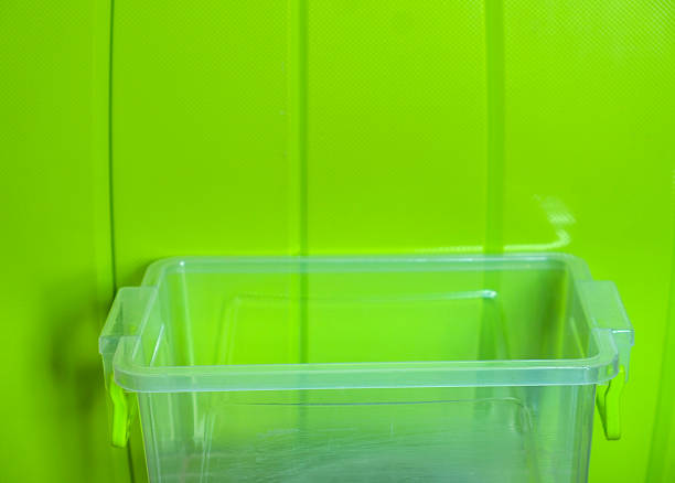 Empty transparent plastic food container with handles set against a vibrant green background, offering a modern and visually appealing composition for food storage and organization