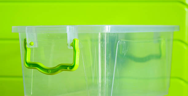 istock Transparent plastic storage box with green handle on green background 2230706358