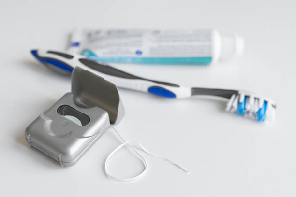 Toothbrush tooth paste and floss on white table