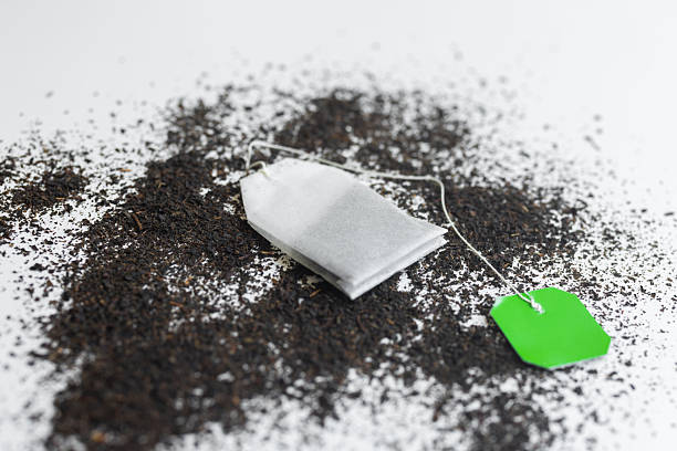 Teabag with open tea leaves on white background