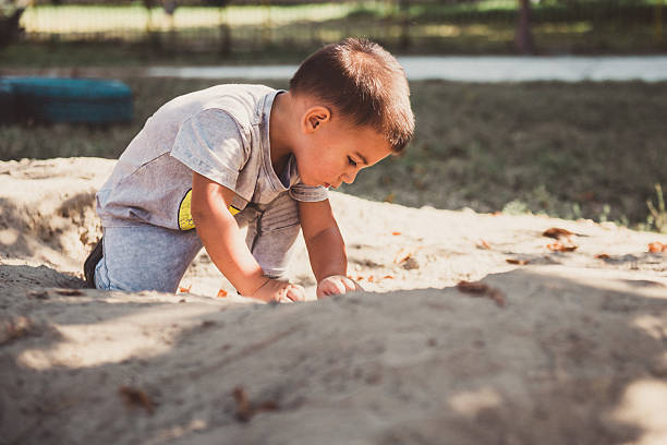 istock Toddler playing with sand in playground on sunny day 2230713953
