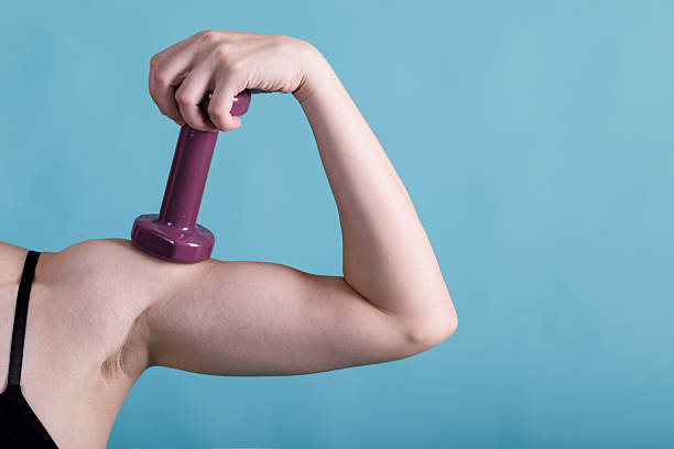 istock Healthy habits and achieving physical wellness, A determined woman flexing her arm while holding a dumbbell, showcasing her strength and dedication to fitness, isolated on blue long banner 2230717378