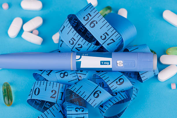 istock Blue surface featuring healthcare objects: semaglutide pens, scattered pills, pill bottle and measuring tape. 2230718294