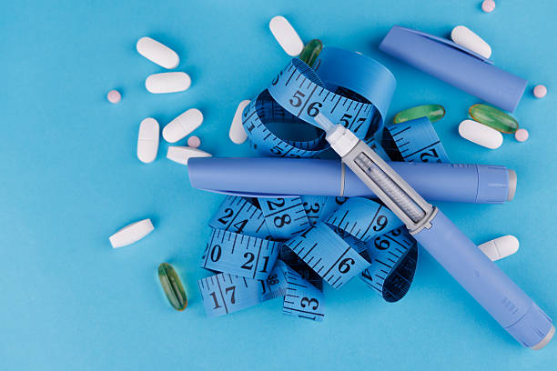 istock Intense blue table showing semaglutide pens, scattered tablets, pill bottle and measuring tape. 2230719464