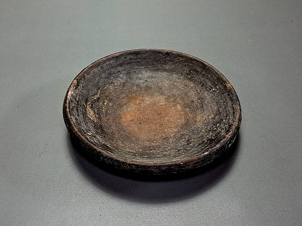 istock Rustic wooden bowl sits centered on a grey surface, showing its aged texture and organic form. 2230721209