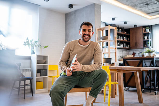 istock Young man holding digital tablet and smiling at home 2230721650