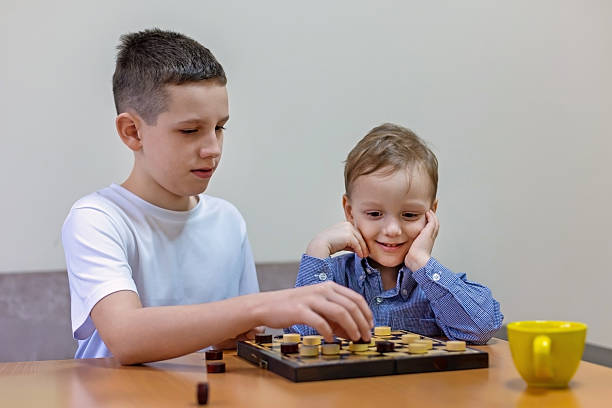 istock Two brothers playing checkers at home. 2230723404