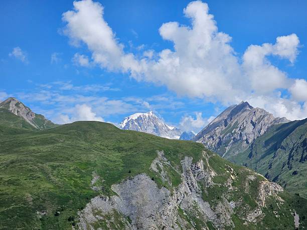 La Thuile, Val D'Aosta, July 02 2025: Panoramic view to the alps, beautiful green landscape reflected in a small natural lake. Beautiful blue sky with some clouds. Mountains with a little snow. Aerial view to the little village of La Thuile.