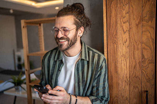 istock Young man smiling and using smartphone at home 2230724252