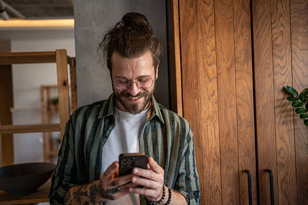 istock Young man smiling and using smartphone at home 2230724275