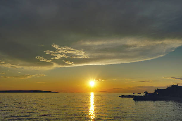 Big dark clouds above sea surface during the shiny golden sunset