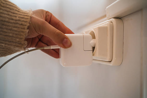 istock Woman plugging a white phone charger into a wall socket 2230725050