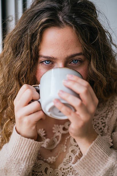 istock Young woman drinking a warm beverage at home 2230725946