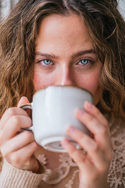 istock Young woman with blue eyes drinking a warm beverage from a mug 2230725956